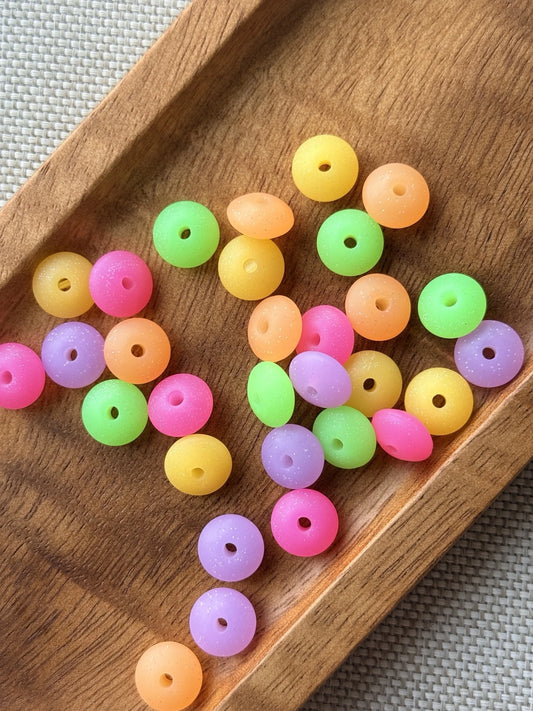 30-count mix of colorful 12mm glow in the dark silicone lentil spacer beads in pink, green, purple, yellow and orange for keychains, wristlets, pens and DIY crafts.