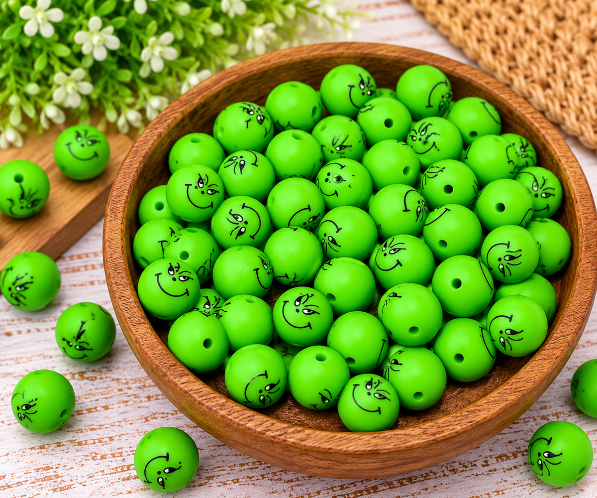 Bright neon green silicone beads with black smiling face prints displayed in a wooden tray