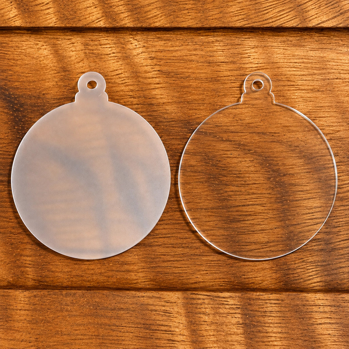3-inch round acrylic ornament blank with protective film and a hanging hole, displayed on a wooden surface.