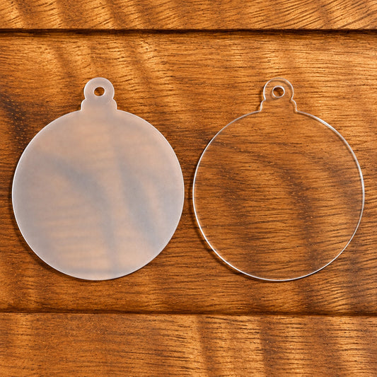 3-inch round acrylic ornament blank with protective film and a hanging hole, displayed on a wooden surface.
