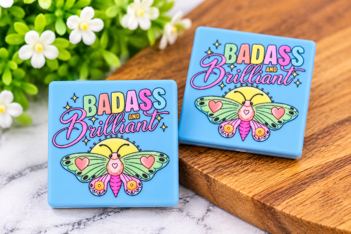 Blue Badass and Brilliant silicone focal bead featuring a colorful butterfly design with pink, mint and yellow details.