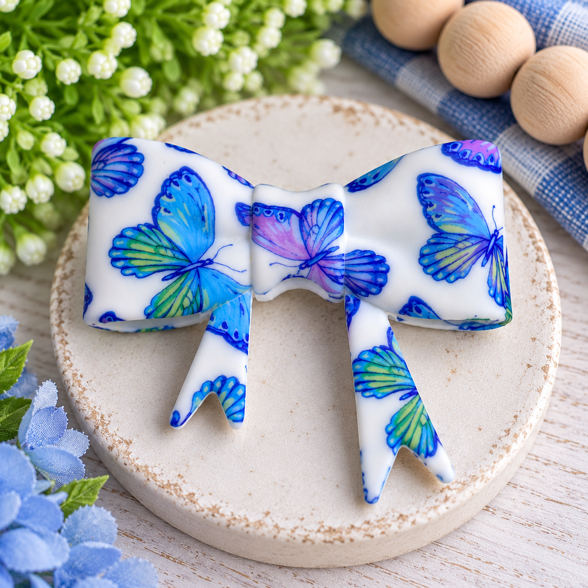 Large white silicone bow focal bead with colorful blue, green, purple and pink butterfly print for DIY beading projects.
