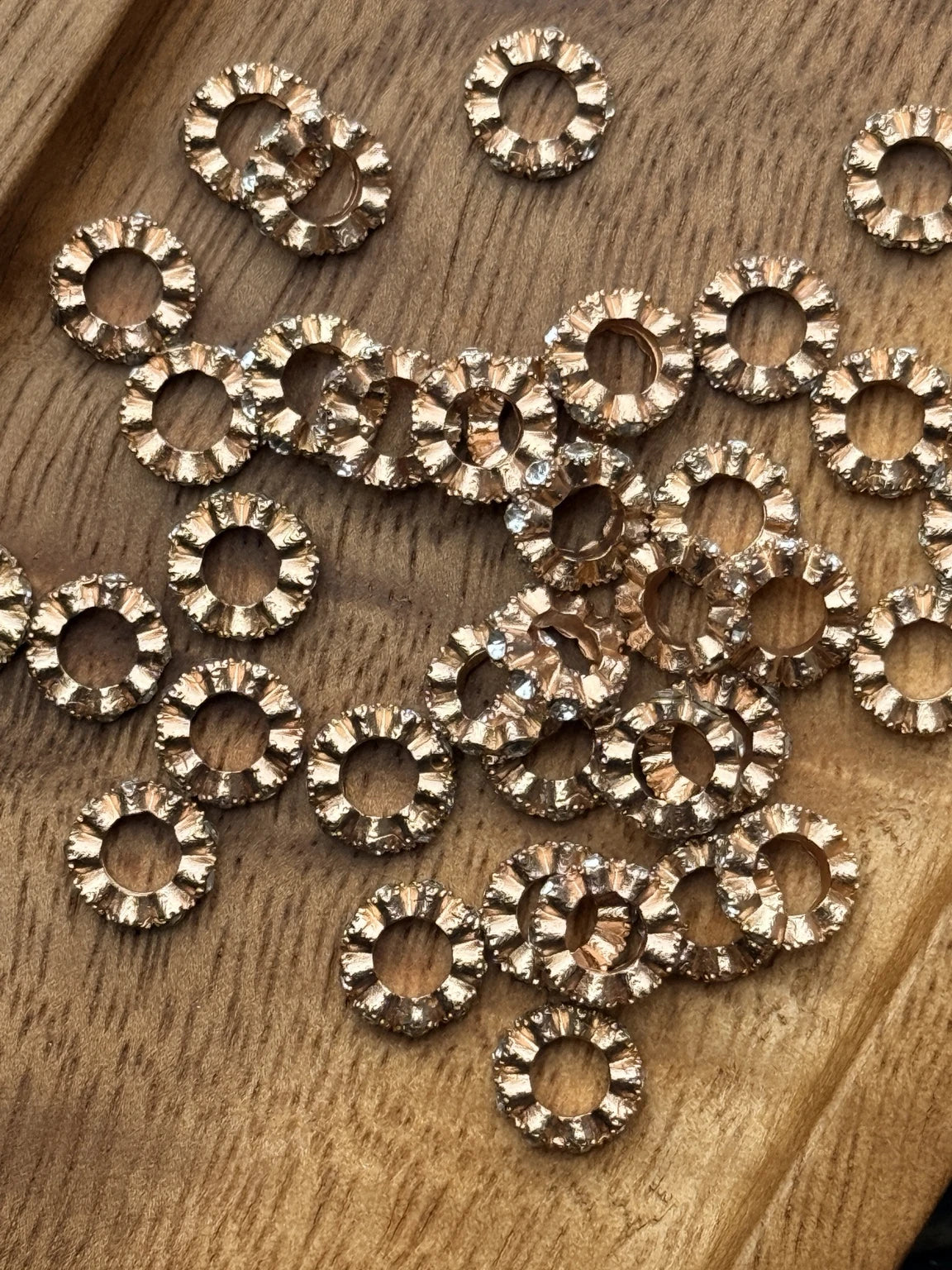 Rose gold 10mm metal spacer beads with clear rhinestone accents and textured design. Perfect for adding elegant sparkle to handmade creations. Sold in 20-count bags.