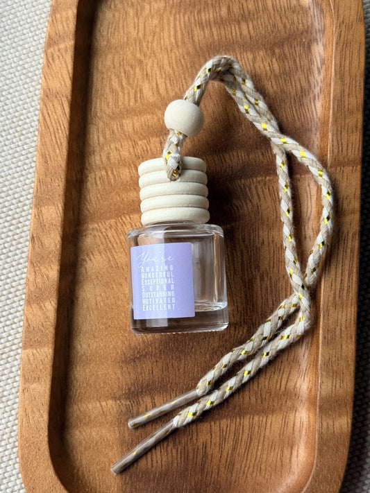 Empty refillable glass and wood hanging car diffuser bottle by Four Seasons of Happiness with natural wooden cap, decorative hanging cord, and colorful “You’re Awesome” label. Holds your favorite fragrance or essential oil and is sold individually.