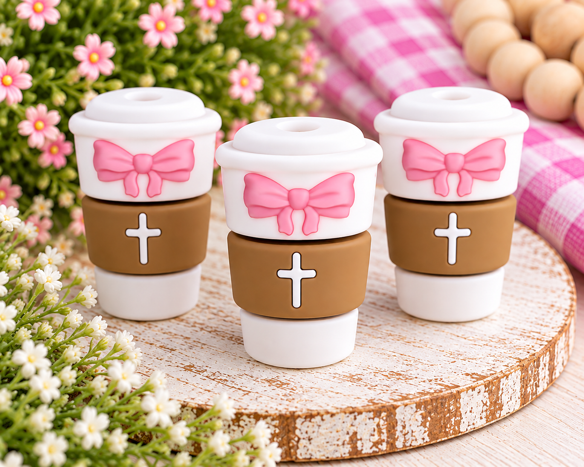White and brown coffee cup silicone focal bead featuring a pink bow and white cross accent for DIY beading projects.