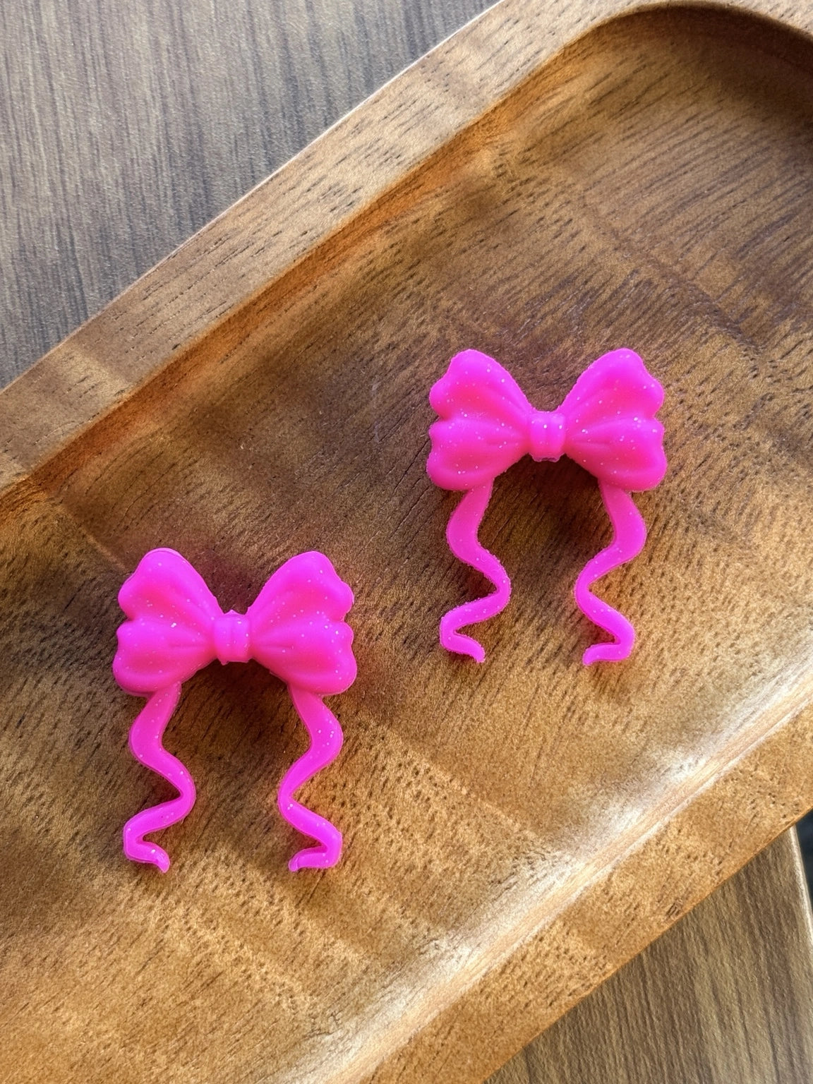     Bright fuchsia pink silicone focal bead featuring a glitter-accented ribbon bow with flowing tails, perfect for beadable pens, keychains, wristlets, badge reels, and DIY craft projects.