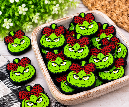 Close-up of bright green silicone holiday focal beads with yellow eyes, black outlines, and oversized spotted bows