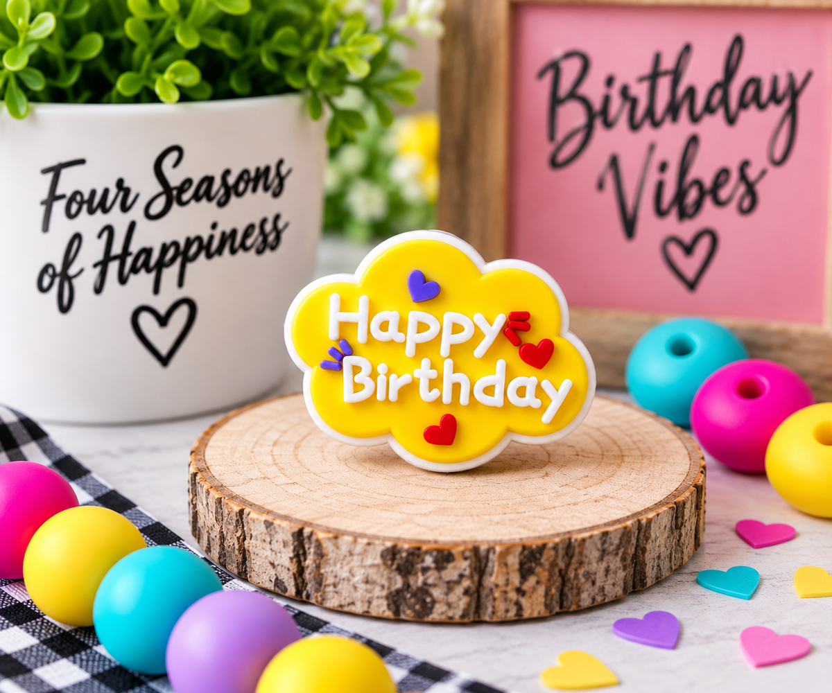 Yellow Happy Birthday silicone focal bead with raised white lettering and colorful heart accents, sold individually by Four Seasons of Happiness.