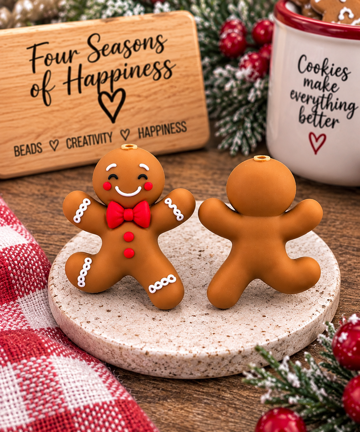 Happy gingerbread man silicone focal bead featuring a brown gingerbread character with red bow tie, red buttons, white icing details and smiling face, shown from front and back.