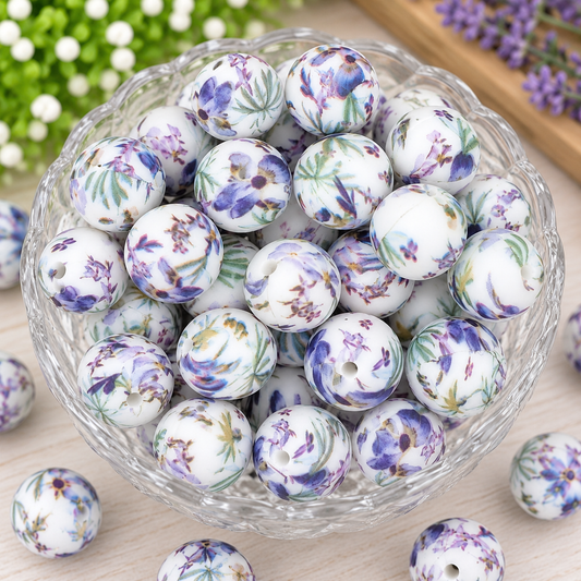 Lavender Meadow 15mm printed silicone beads featuring purple watercolor flowers, green botanical leaves, and a white background displayed in a clear bowl.