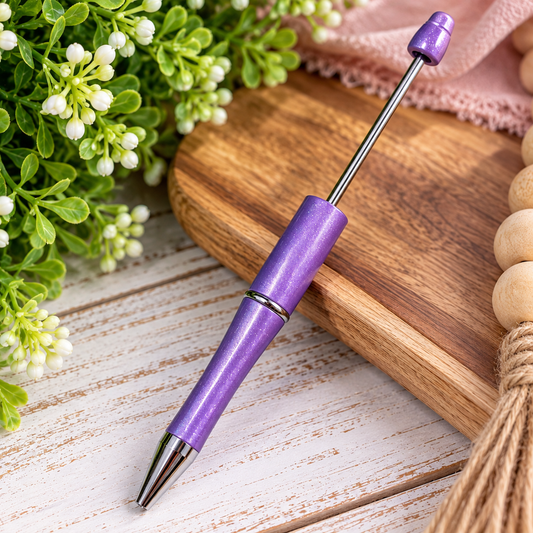 Lilac Dreams purple shimmer beadable pen with a sparkling lavender finish, silver metal accents, and removable beadable rod, displayed on a wooden tray with lavender flowers.