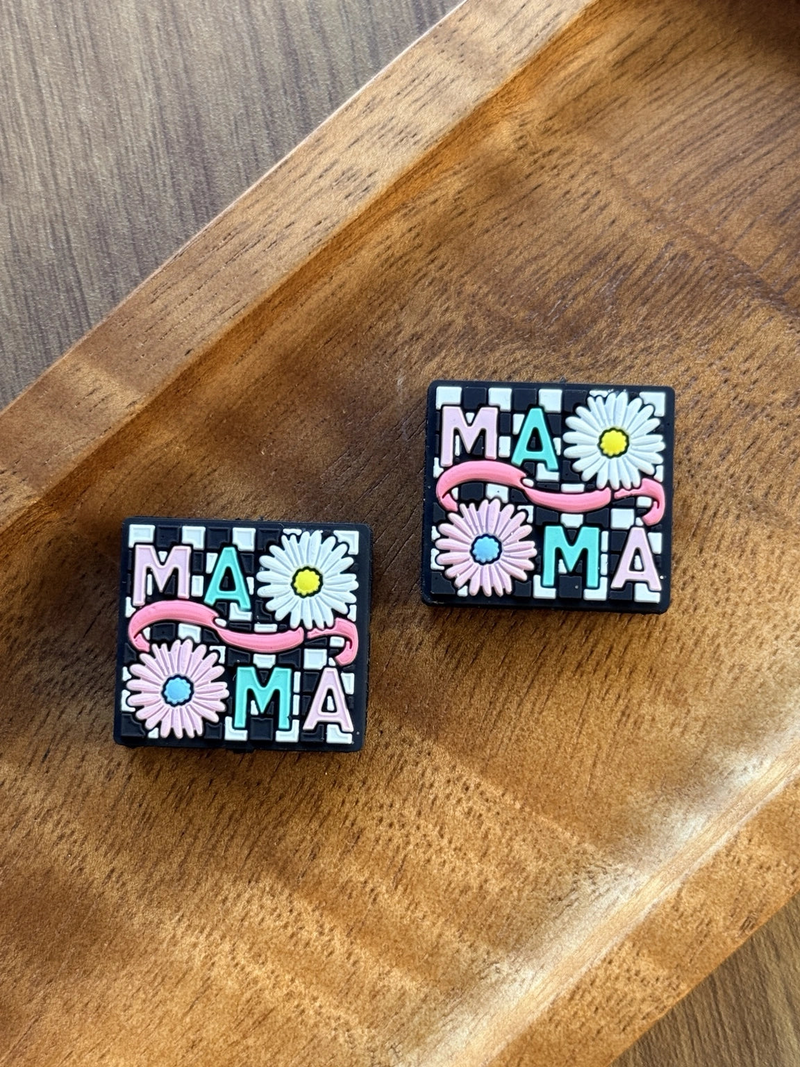Floral Mama silicone focal bead featuring daisy accents, pink and aqua MAMA lettering, and a black and white checkered background for beadable pens, keychains, wristlets, and badge reels.