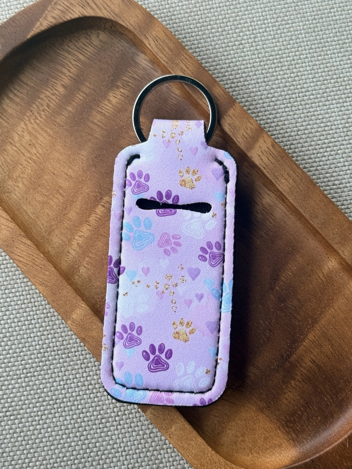 Paw print neoprene chapstick holder keychain with metal key ring, designed to hold standard lip balm and attach to keys, purses, backpacks or bags.