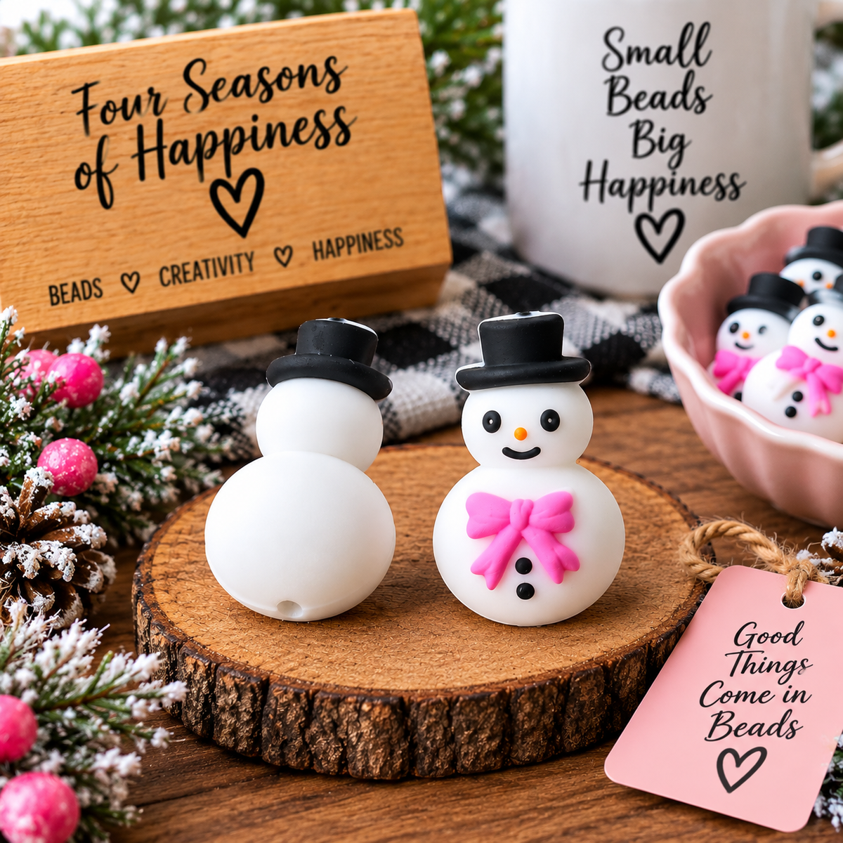 White snowman silicone focal bead with a black top hat, bright pink bow, orange nose and black button details, styled in a cozy winter setting for Four Seasons of Happiness.