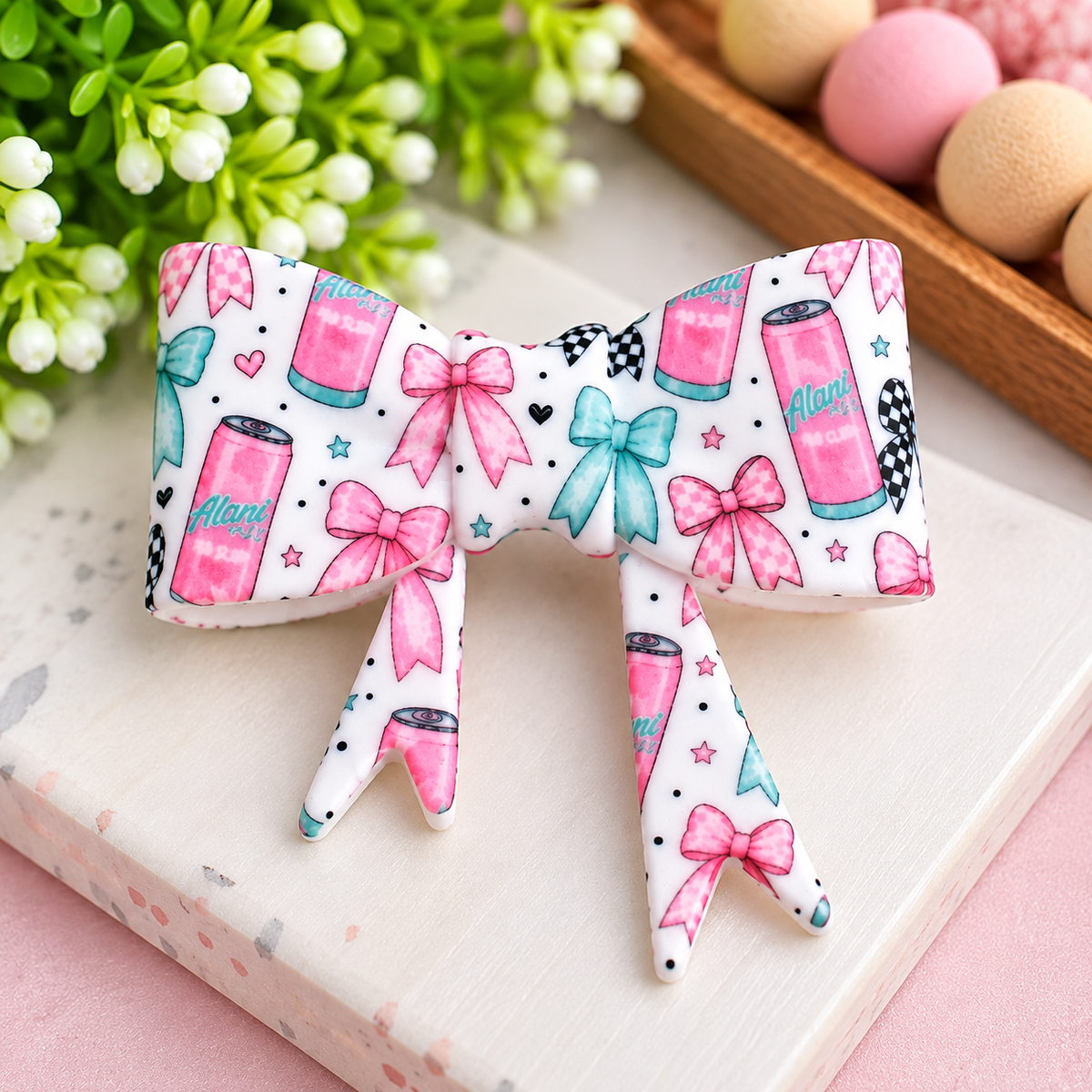 Large white silicone bow focal bead with pink and aqua bows, hearts, stars and energy drink-inspired details, sold individually.