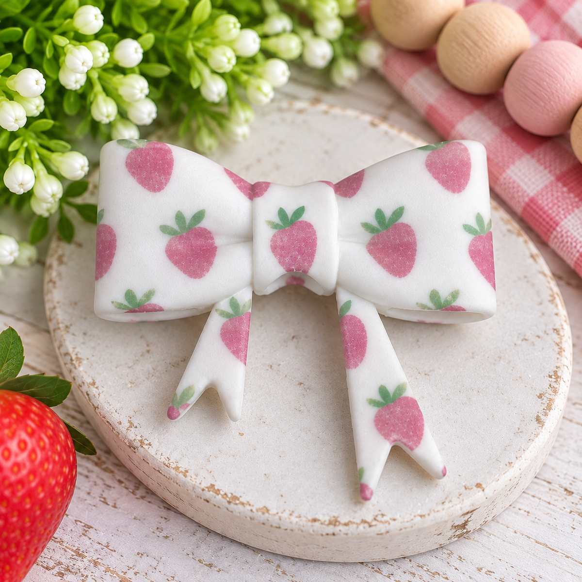 Large white silicone bow focal bead with an all-over pink strawberry and green leaf print, sold individually.