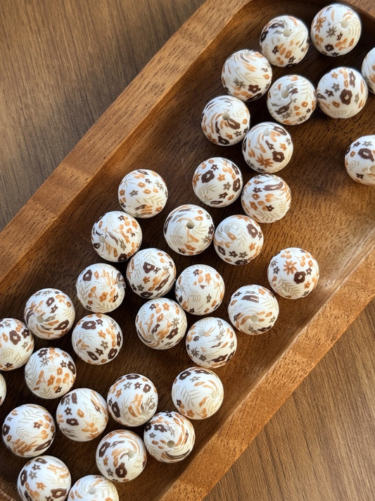     15mm printed silicone beads featuring delicate floral and botanical designs in caramel, mocha, honey, and cream tones on a white background, perfect for beadable pens, wristlets, keychains, badge reels, and DIY craft projects