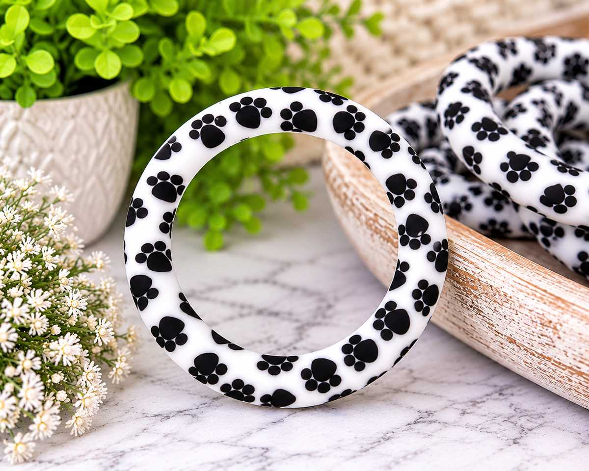 Happy Paws 65mm silicone ring bead featuring black paw prints on a white background for pet-themed wristlet keychains and DIY crafts.