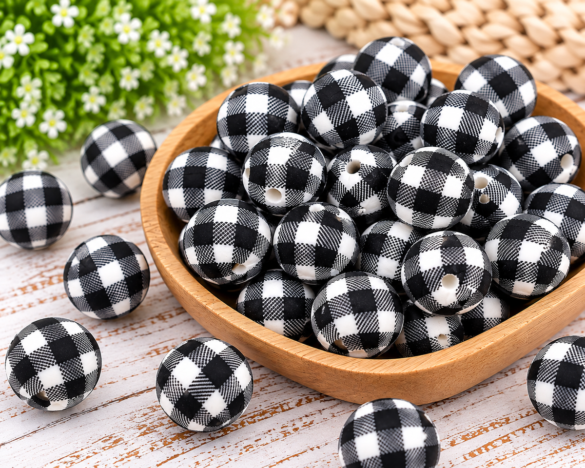 Close-up of round 15mm black and white buffalo check silicone beads showing detailed plaid print and bead holes.