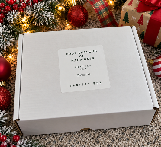 Four Seasons of Happiness Christmas variety craft box featuring holiday beads and beadable supplies in festive red, green, and white colors, packaged in a white gift box surrounded by Christmas decorations.