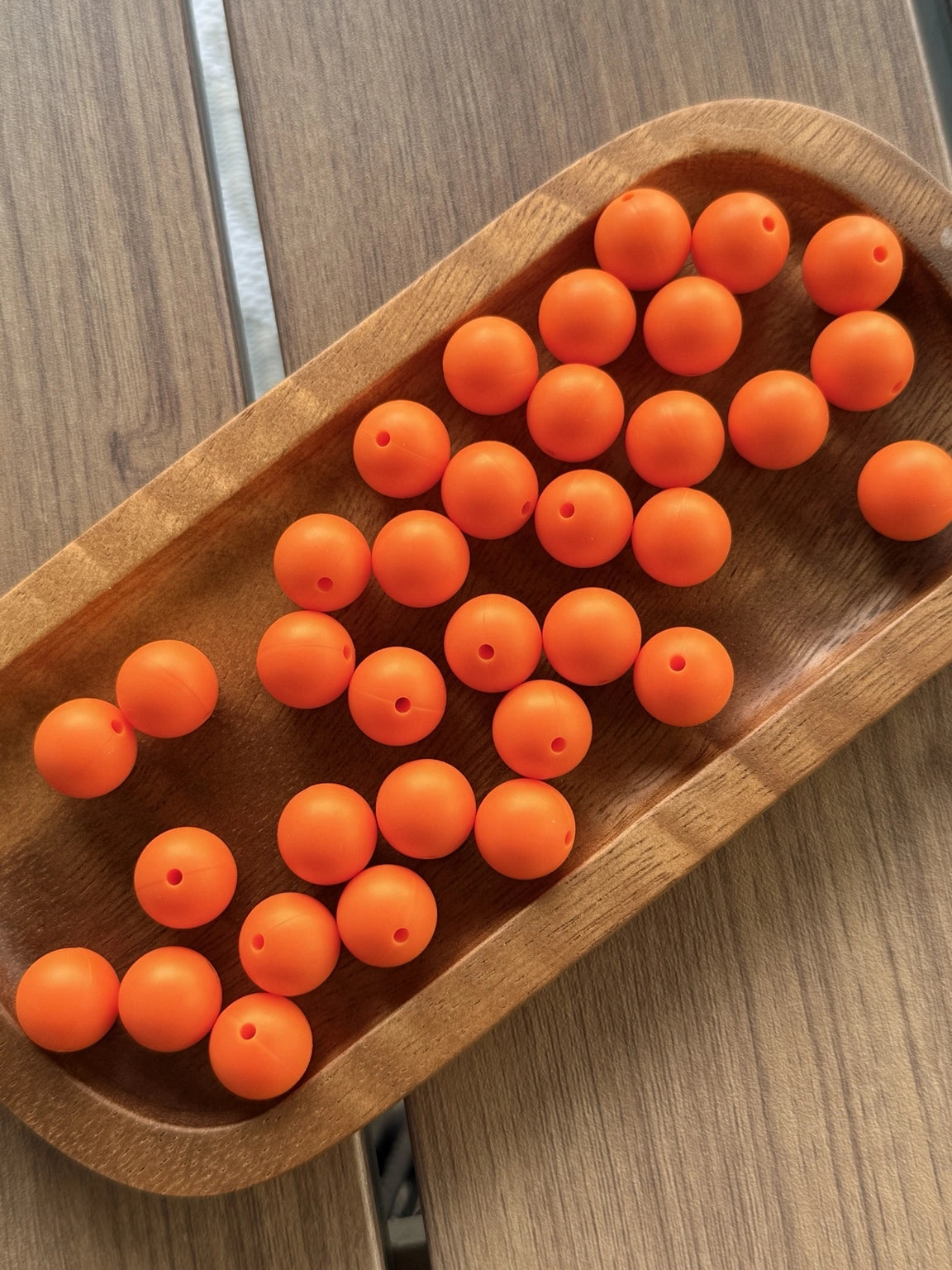 Bright orange 15mm matte silicone round beads displayed on a wooden tray for beadable pens, jewelry making, wristlets, and DIY craft projects by Four Seasons of Happiness
