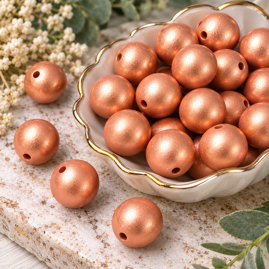Close-up of 15mm Copper Kisses silicone beads showing their rose-gold metallic shimmer and round shape
