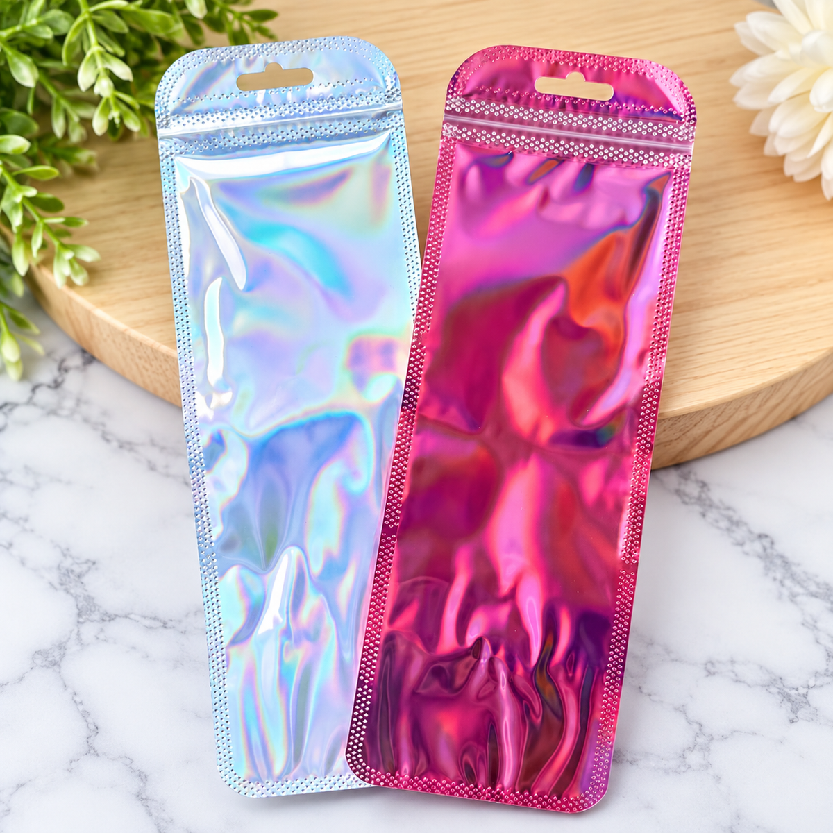 Double-sided holographic zip bags for beaded pen packaging in iridescent silver and metallic pink, featuring resealable closures and hanging holes for handmade pen gifts and retail displays.