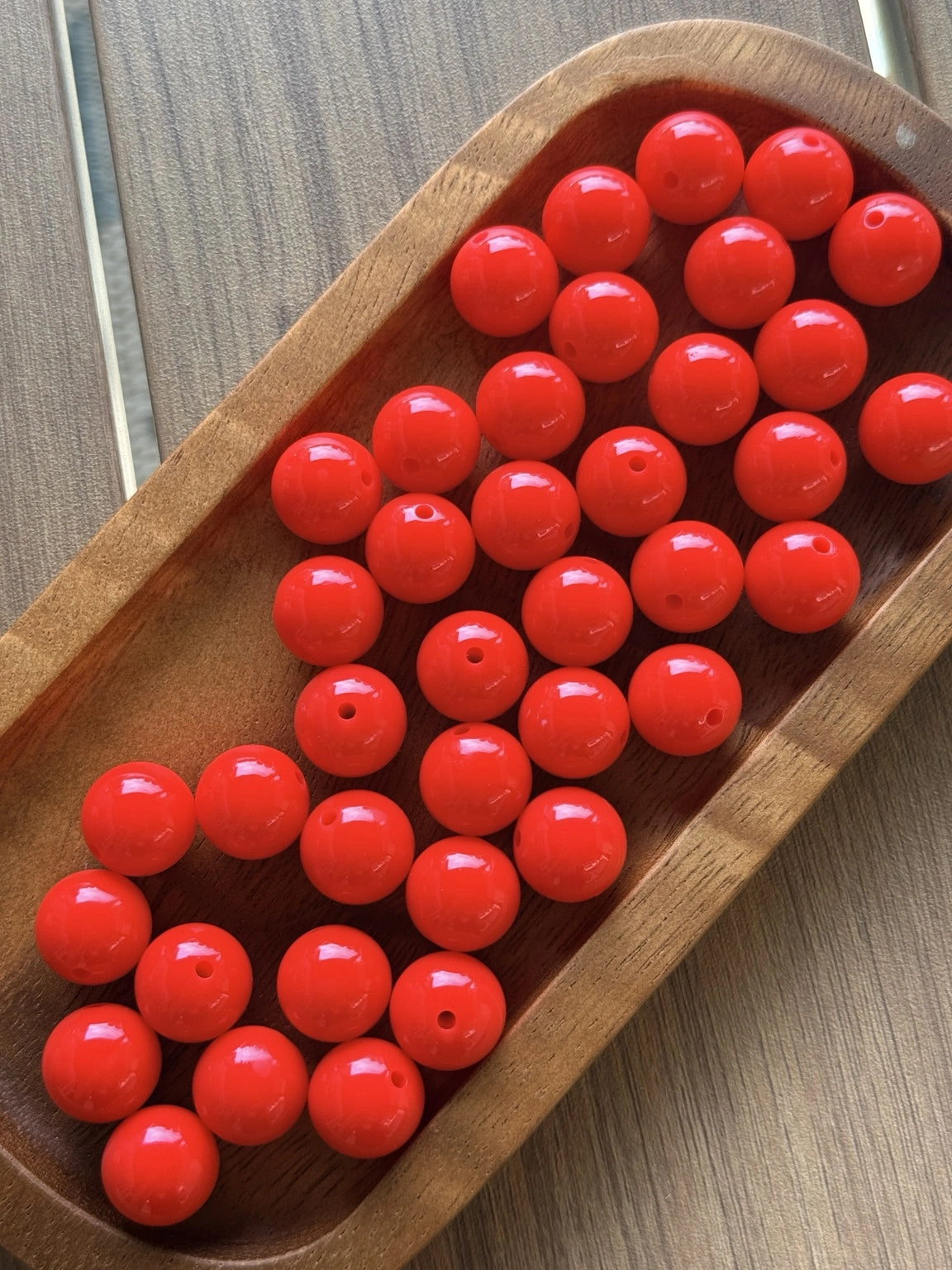 Glossy Cherry Pop Liquid 15mm silicone beads from Four Seasons of Happiness displayed in a wooden tray. Premium food-grade silicone beads sold individually for beaded pens, wristlets, keychains, badge reels, jewelry making, and DIY craft projects