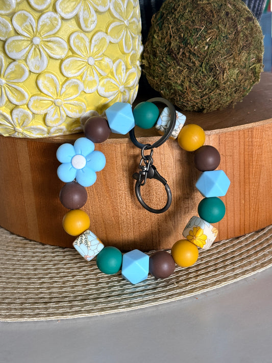 FSOH silicone wristlet keychain with blue flower bead and earthy tones including brown, yellow, and teal beads