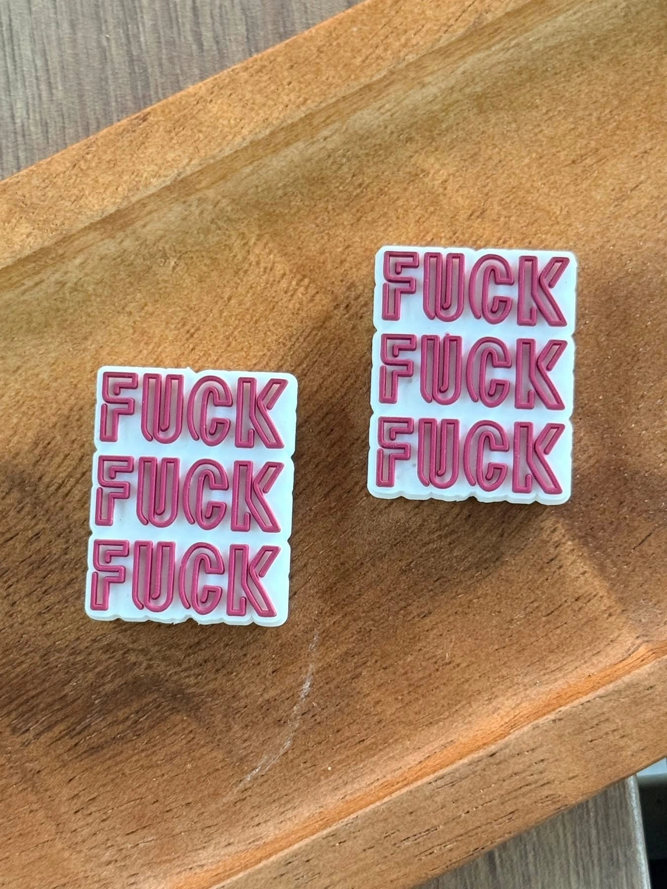 Funny adult humor silicone focal bead featuring bold text design displayed on a wooden tray. Ideal for beadable pens, keychains, wristlets, badge reels, lanyards, and custom DIY crafting projects.