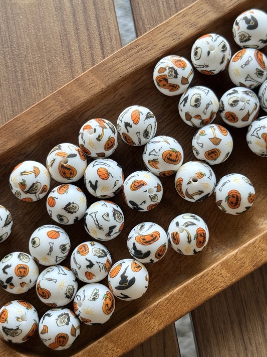 White 15mm silicone printed bead featuring pumpkins, ghosts, bats, candy, skulls, brooms, and Halloween icons for seasonal keychains, wristlets, pens, and DIY craft projects.