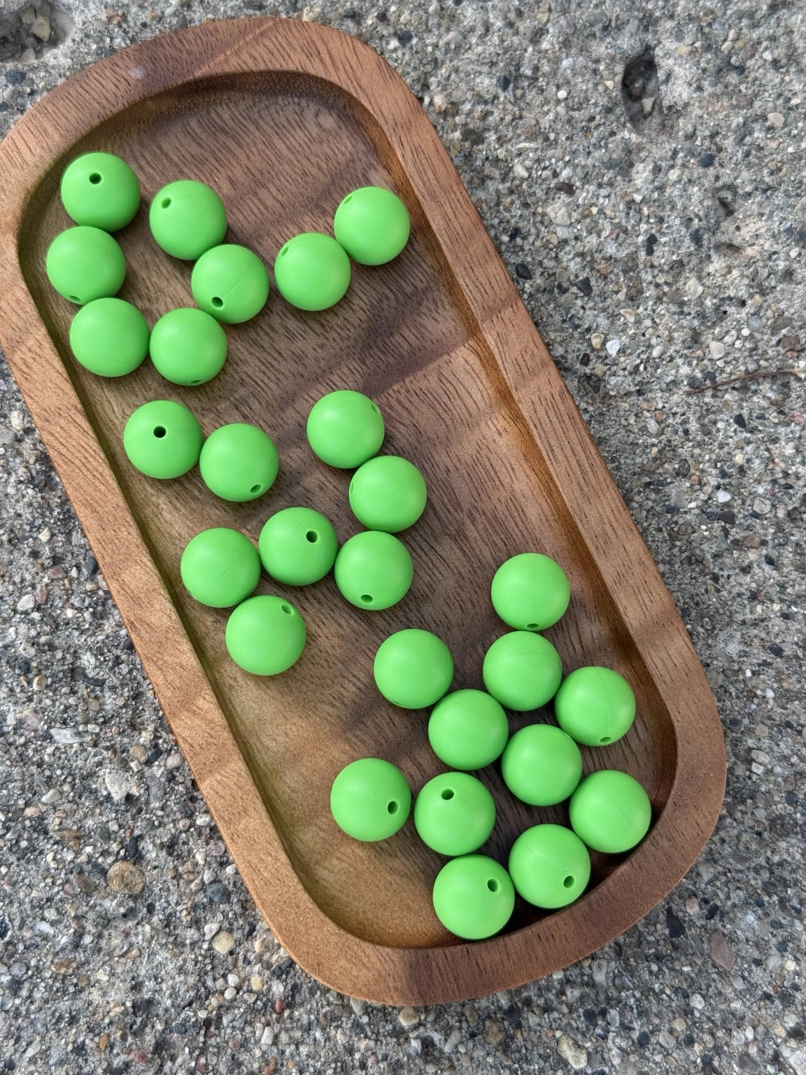 Meadow Green 15mm matte grass green silicone round beads displayed on a wooden tray for beaded pens, wristlets, keychains, badge reels and DIY crafts.