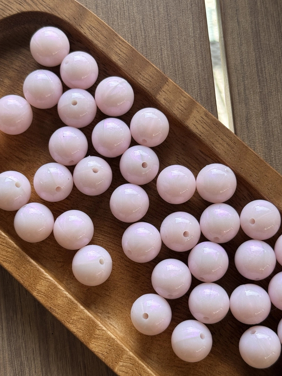 Glossy Pearl Blush Liquid Shimmer 15mm silicone beads from Four Seasons of Happiness displayed in a wooden tray. Premium food-grade silicone beads sold individually for beaded pens, keychains, wristlets, badge reels, jewelry making, and DIY craft projects.