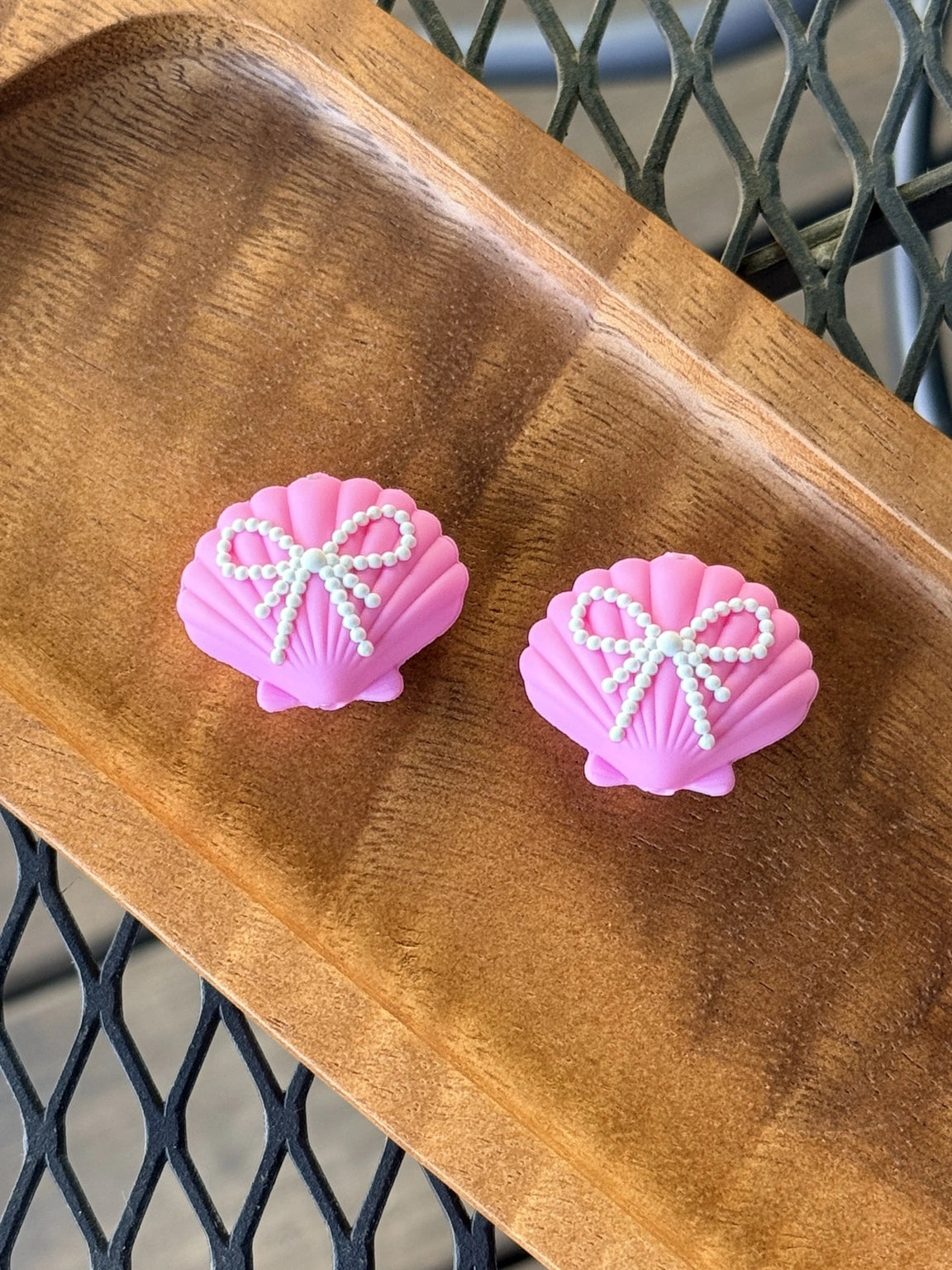 Pink silicone seashell focal bead with pearl bow detail for keychains, wristlets, badge reels, beadable pens, and coastal themed DIY craft projects.