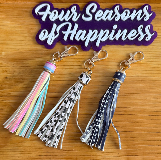Printed faux leather tassel keychain charms with gold hardware from Four Seasons of Happiness featuring pastel rainbow, cow print, and star print designs for DIY keychains and craft accessories
