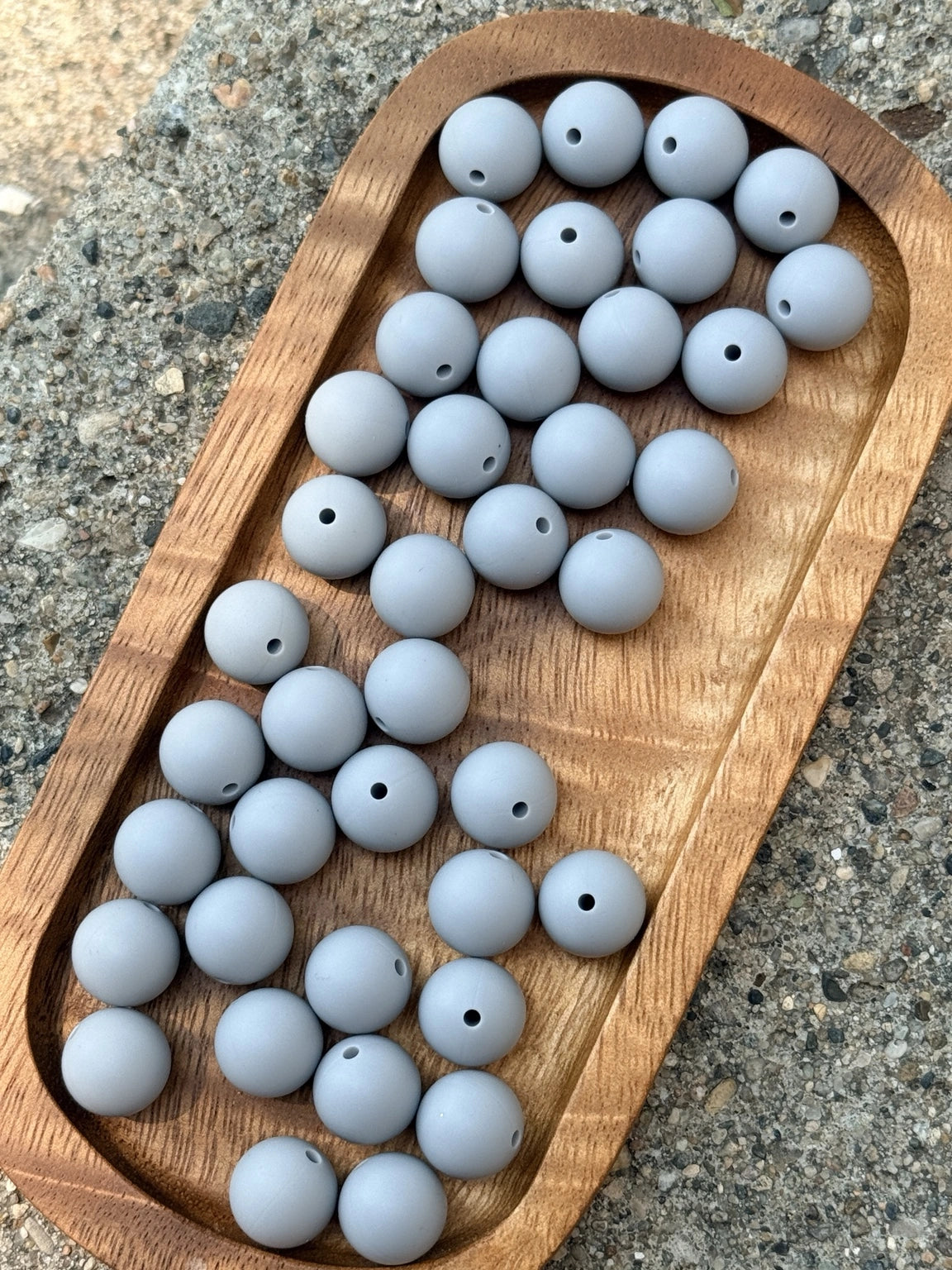 Silver Cloud 15mm matte light gray silicone round beads displayed on a wooden tray for beaded pens, wristlets, keychains, badge reels and DIY crafts.