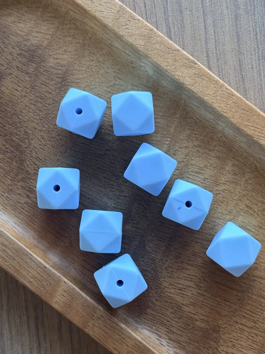     Pastel blue Sky Whisper 14mm silicone hexagon beads displayed in a wooden tray for DIY crafting projects.