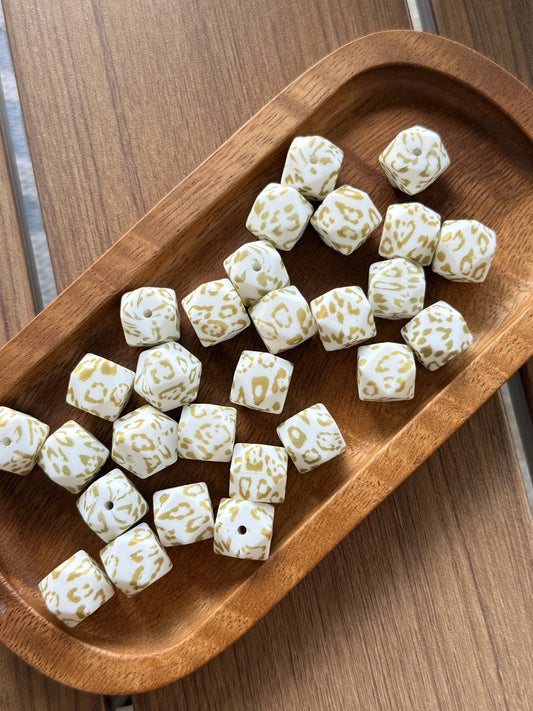 Golden Snow Leopard 14mm printed silicone hexagon beads featuring a white base with gold leopard print design sold in 10 count bags for DIY crafting and beadable projects.