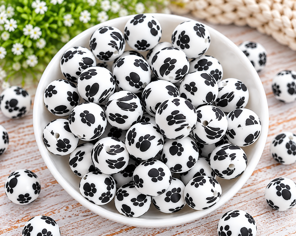 Happy Paws printed silicone beads displayed in a wooden tray for pet-themed wristlets, keychains, and bag charms.