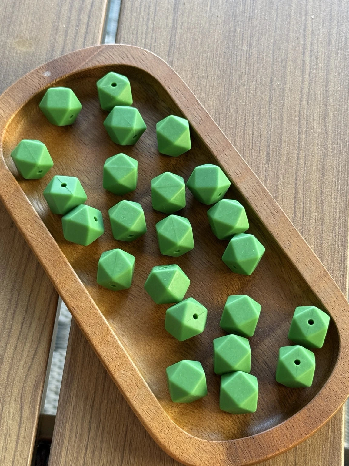 Lucky Clover 14mm matte silicone hexagon beads displayed in a wooden tray. Premium food-grade silicone beads available in 5-count and 10-count bags for beadable pens, keychains, badge reels, wristlets and DIY craft projects.