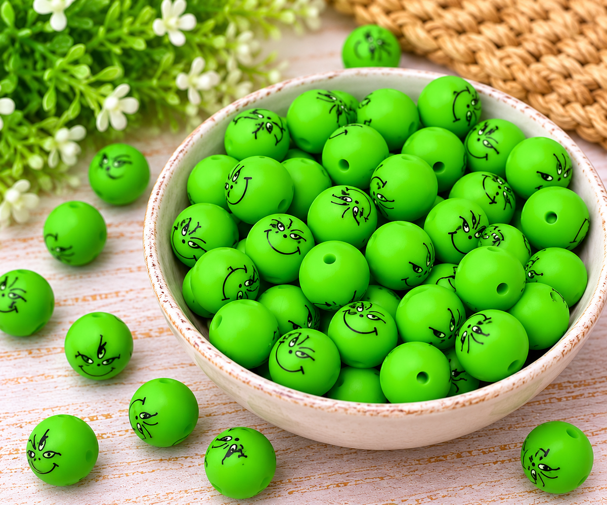 Close-up of 15mm matte green printed silicone beads with a single threading hole and playful black face design