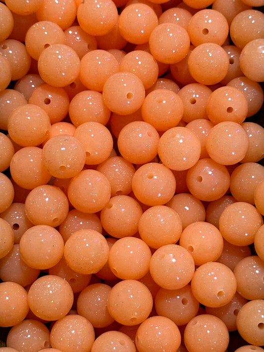 Close-up of peach-colored beads with holes, likely used for jewelry making.