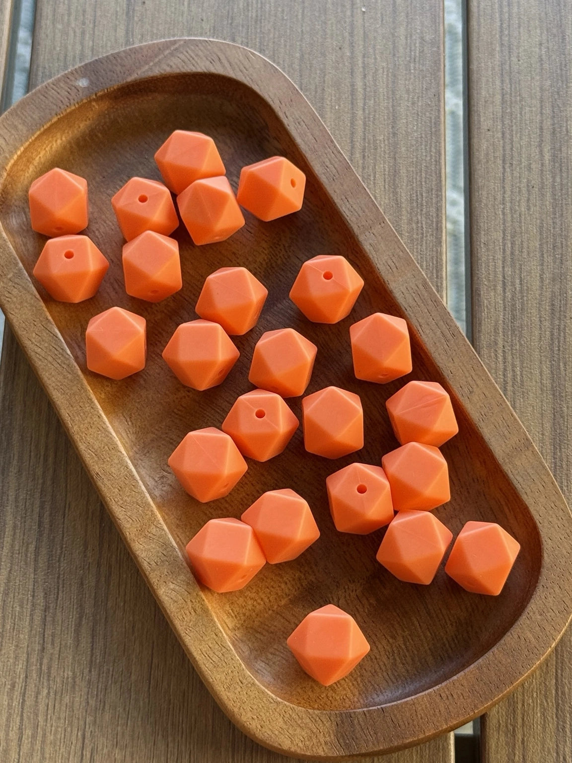 Orange Sorbet 14mm matte silicone hexagon beads displayed in a wooden tray. Premium food-grade silicone beads available in 5-count and 10-count bags for beadable pens, keychains, badge reels, wristlets and DIY craft projects.