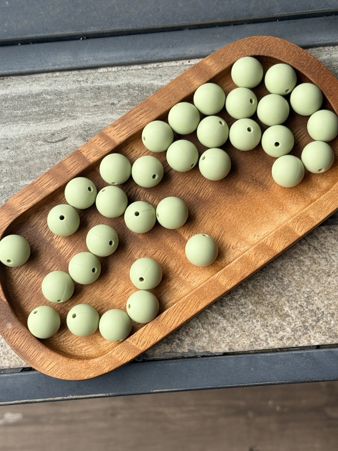 Soft pistachio green 15mm matte silicone round beads displayed on a wooden tray for beadable pens, wristlets, jewelry making, and DIY craft projects by Four Seasons of Happiness