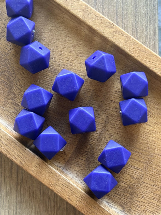 Sapphire Tide 14mm silicone hexagon beads displayed in a wooden tray. These faceted sapphire blue silicone beads are available in 5-count and 10-count bags for beadable pens, keychains, wristlets, badge reels, and DIY craft projects.
