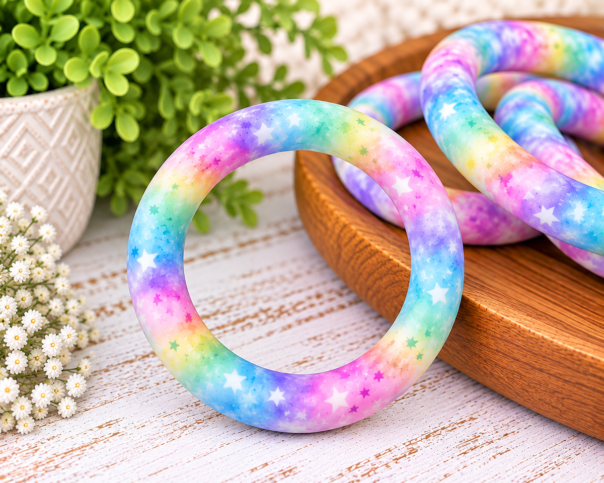 Starlight Wishes 65mm printed silicone ring bead with pastel blue, pink, purple, aqua and yellow colors with scattered stars.