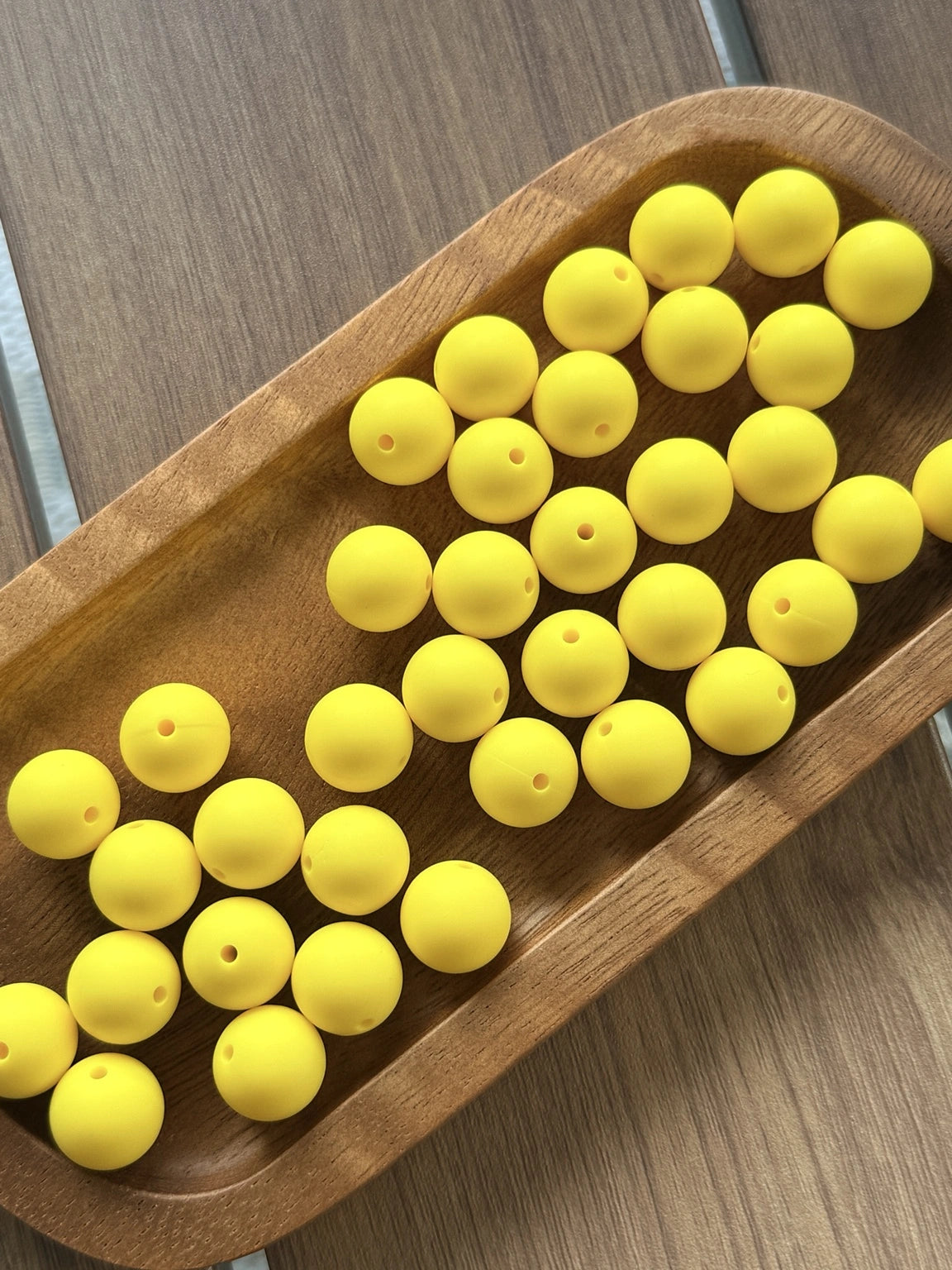 Bright yellow 15mm matte silicone round beads displayed in a wooden tray for crafting, pens, keychains, jewelry making, and beadable accessories.